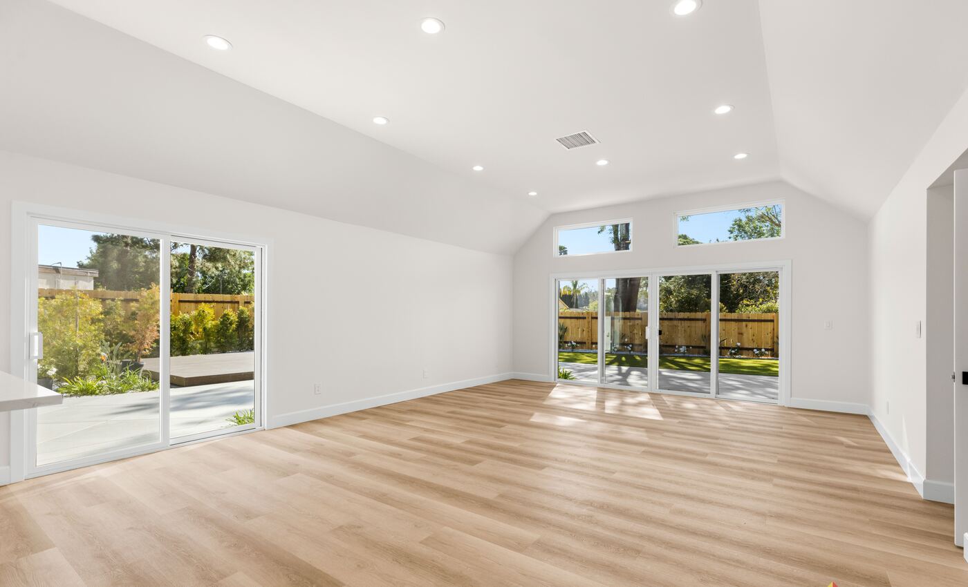 Finished great room with light oak flooring, a vaulted ceiling and sliding doors to the yard, from a Teknik remodel