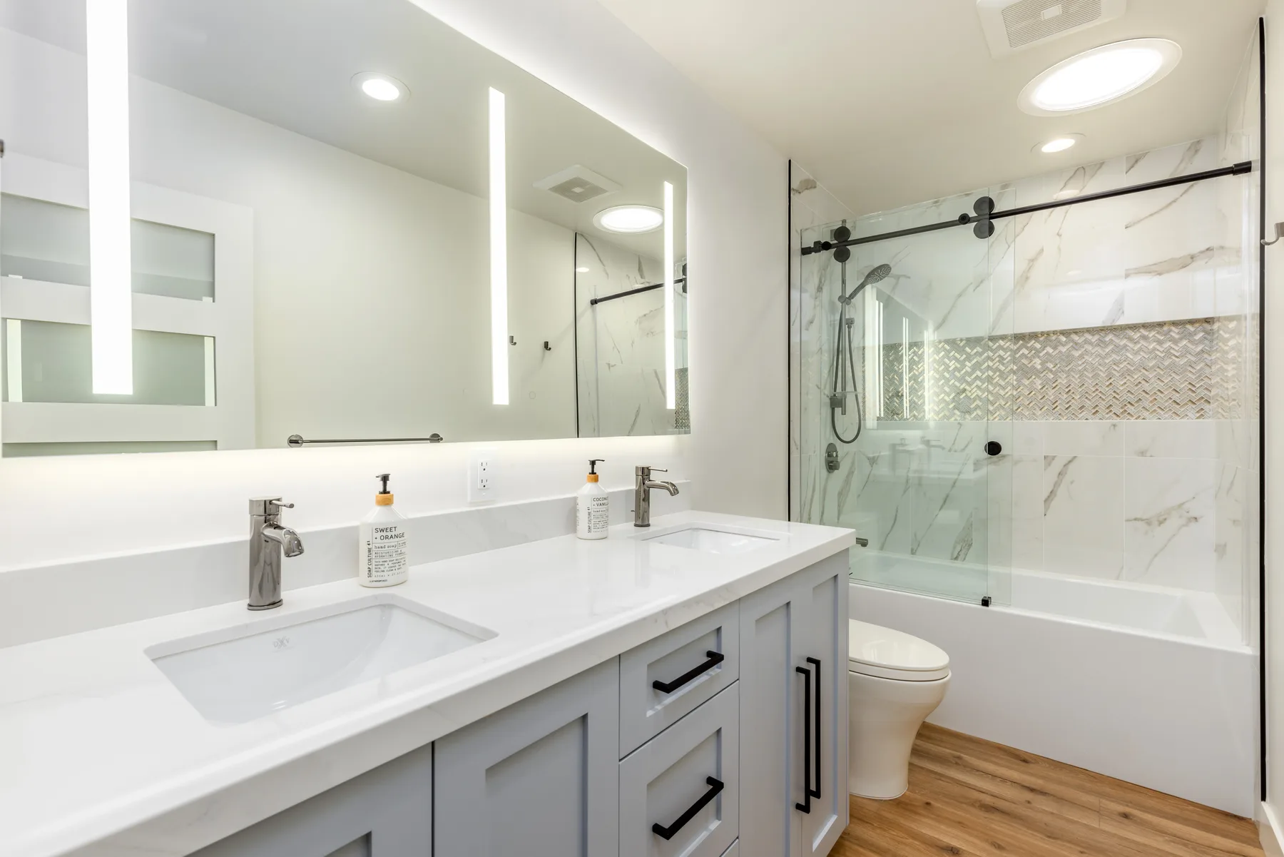 Spa-style master bathroom with a marble shower and double vanity by Teknik Design & Remodeling