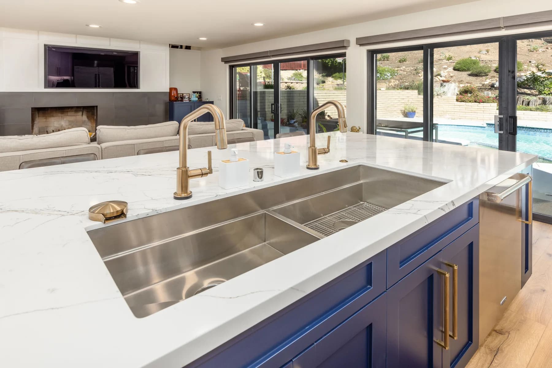 Custom navy kitchen with a waterfall marble island and brass fixtures by Teknik Design & Remodeling