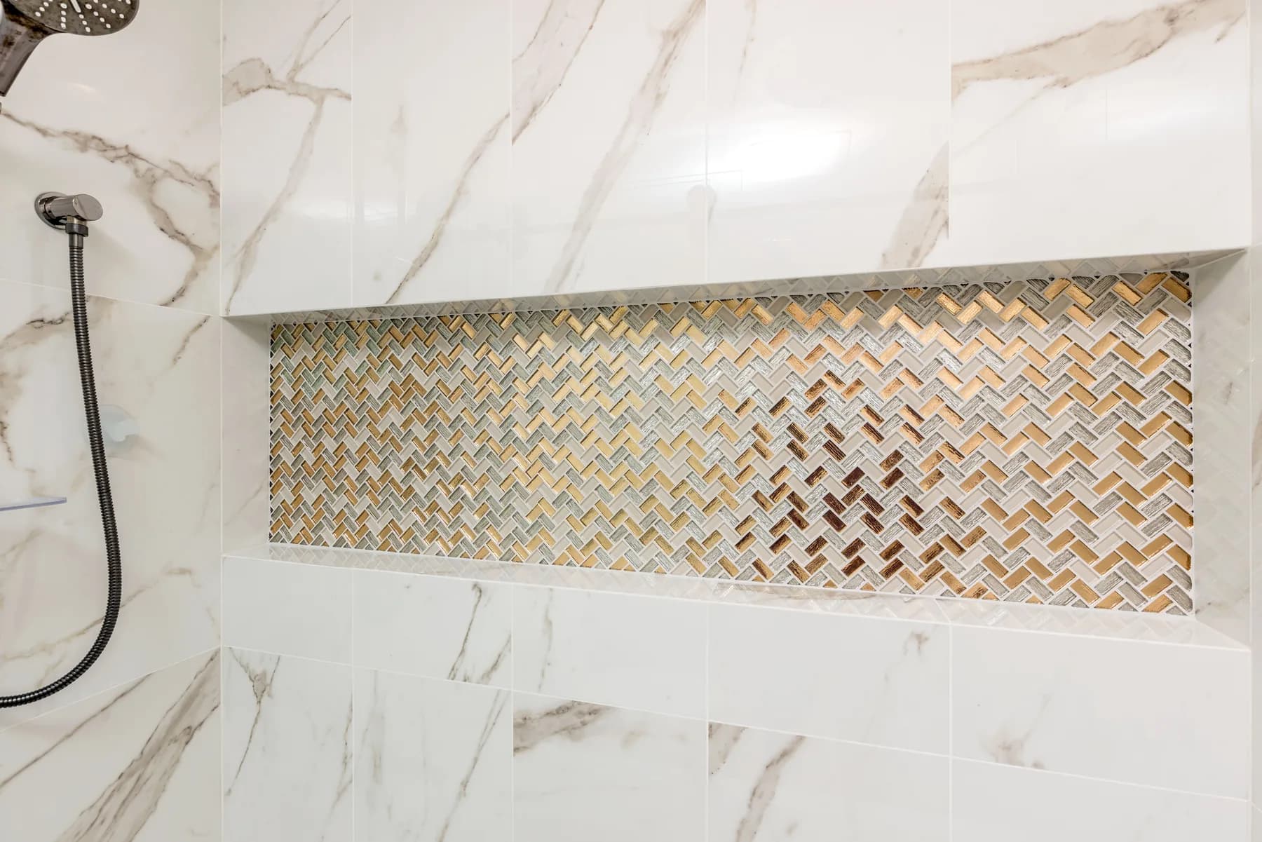 Detailed marble shower wall with a herringbone mosaic niche by Teknik Design & Remodeling