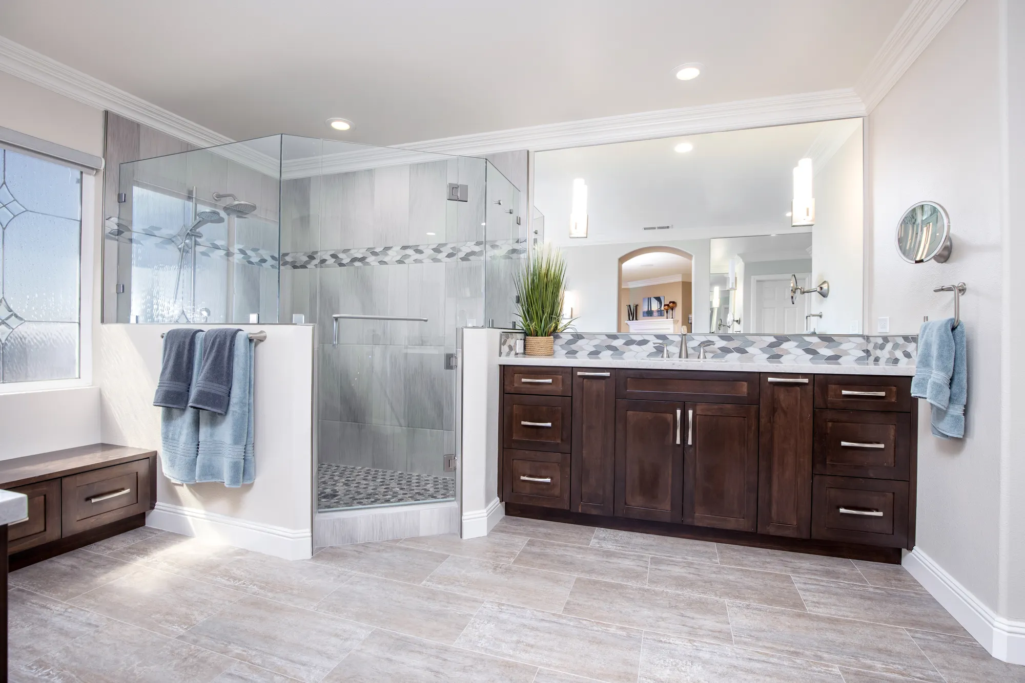Primary bathroom with a glass shower, wood vanity and window seat in Chula Vista