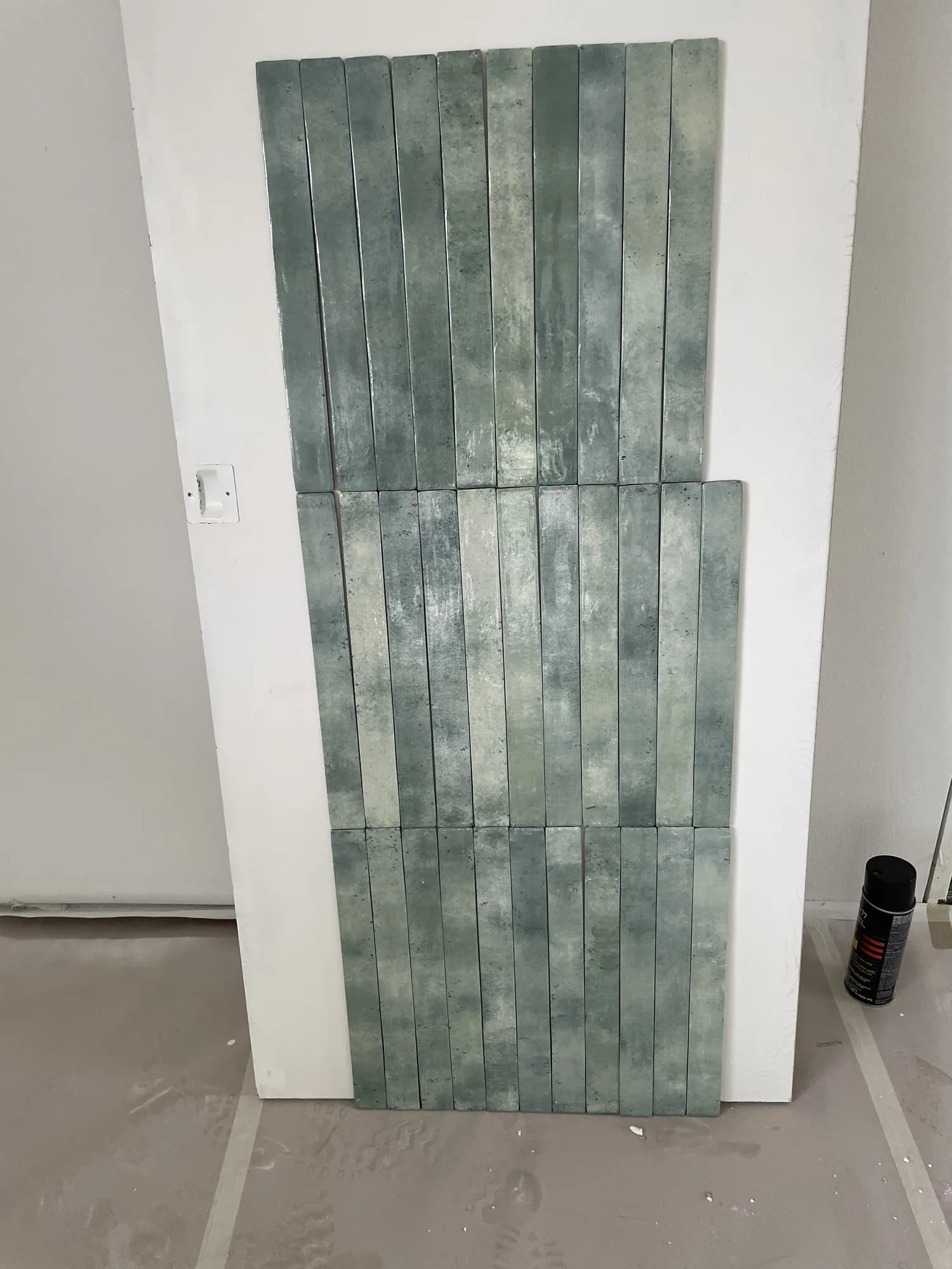 Green glazed tile samples propped against a wall