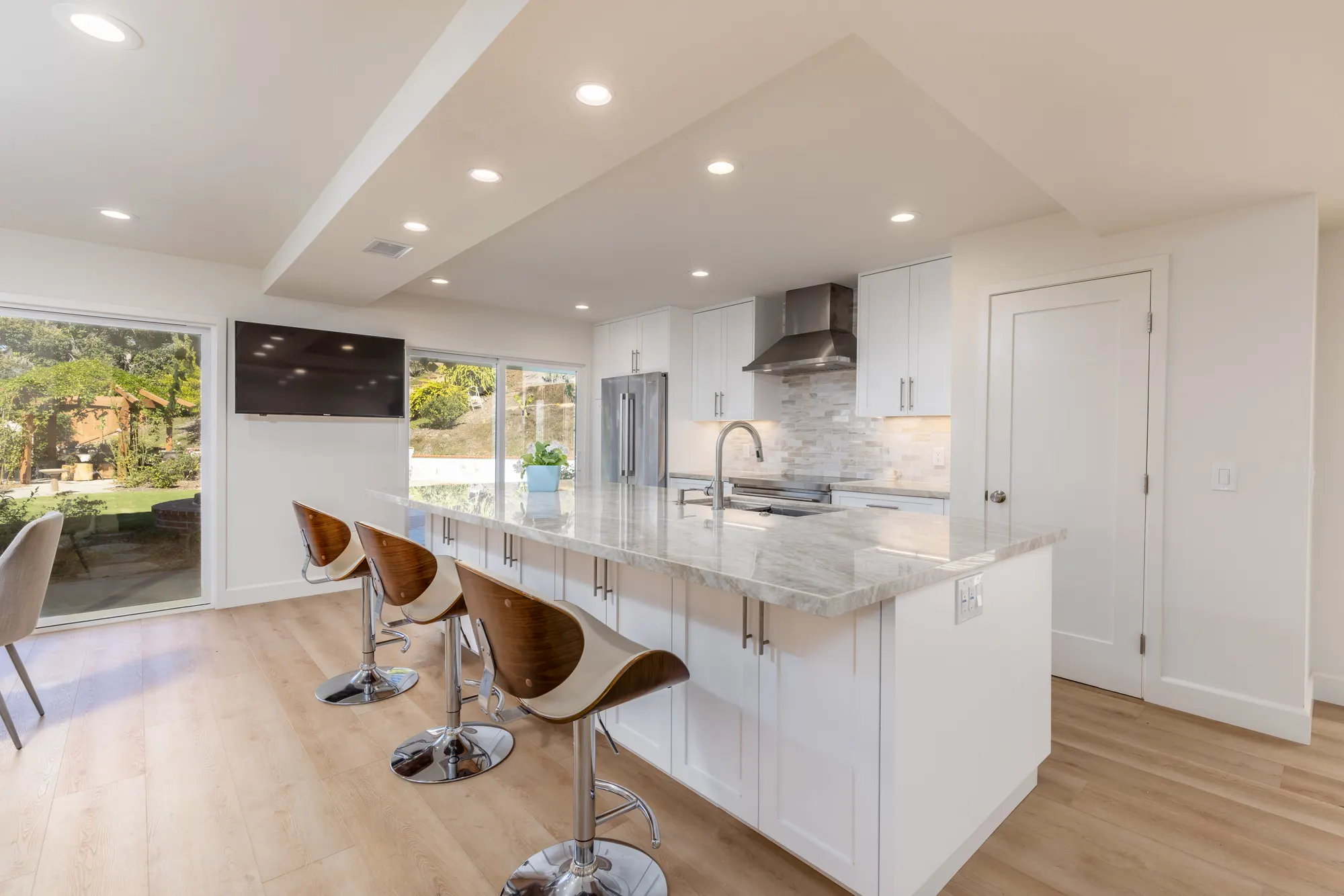 Open kitchen with a long island, white cabinetry and sliding doors to the yard in Rancho Peñasquitos