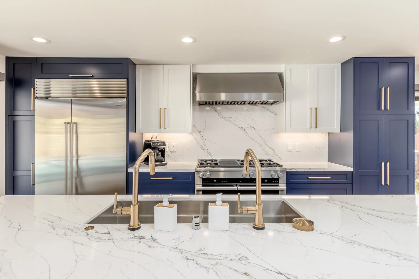 Navy and white marble chef kitchen with brass fixtures after whole house remodel in Scripps Ranch