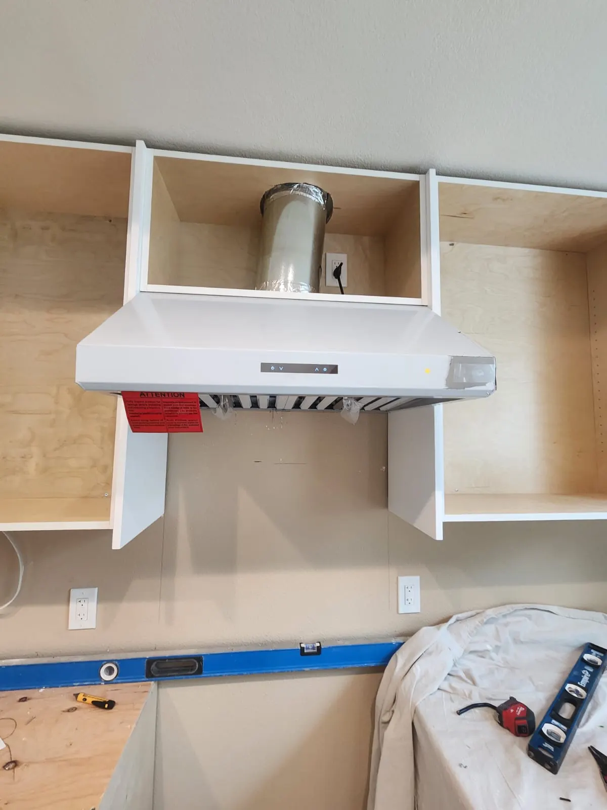 Range hood mounted between unfinished cabinet boxes