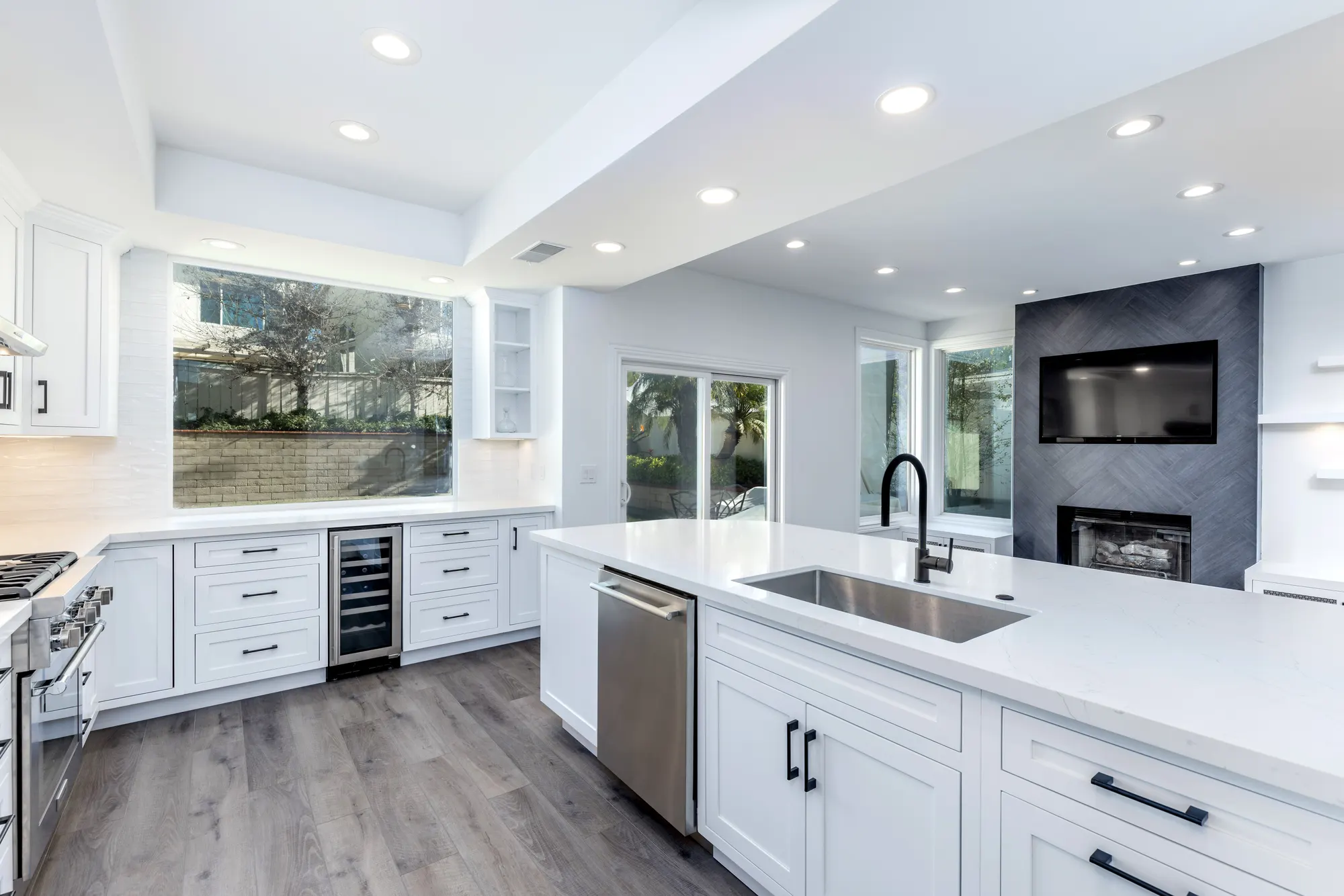 White kitchen with a stone counter and a tiled fireplace beyond in Tierrasanta