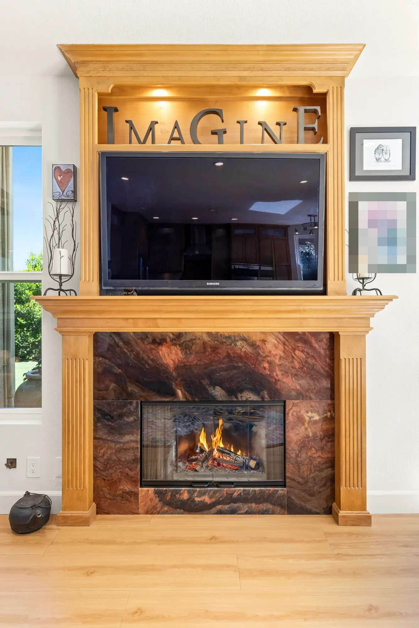 Family room after: a stone fireplace in a wood surround, white walls and light flooring